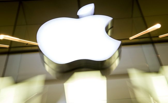 Das Apple-Logo leuchtet an der Fassade des Apple-Stores in München