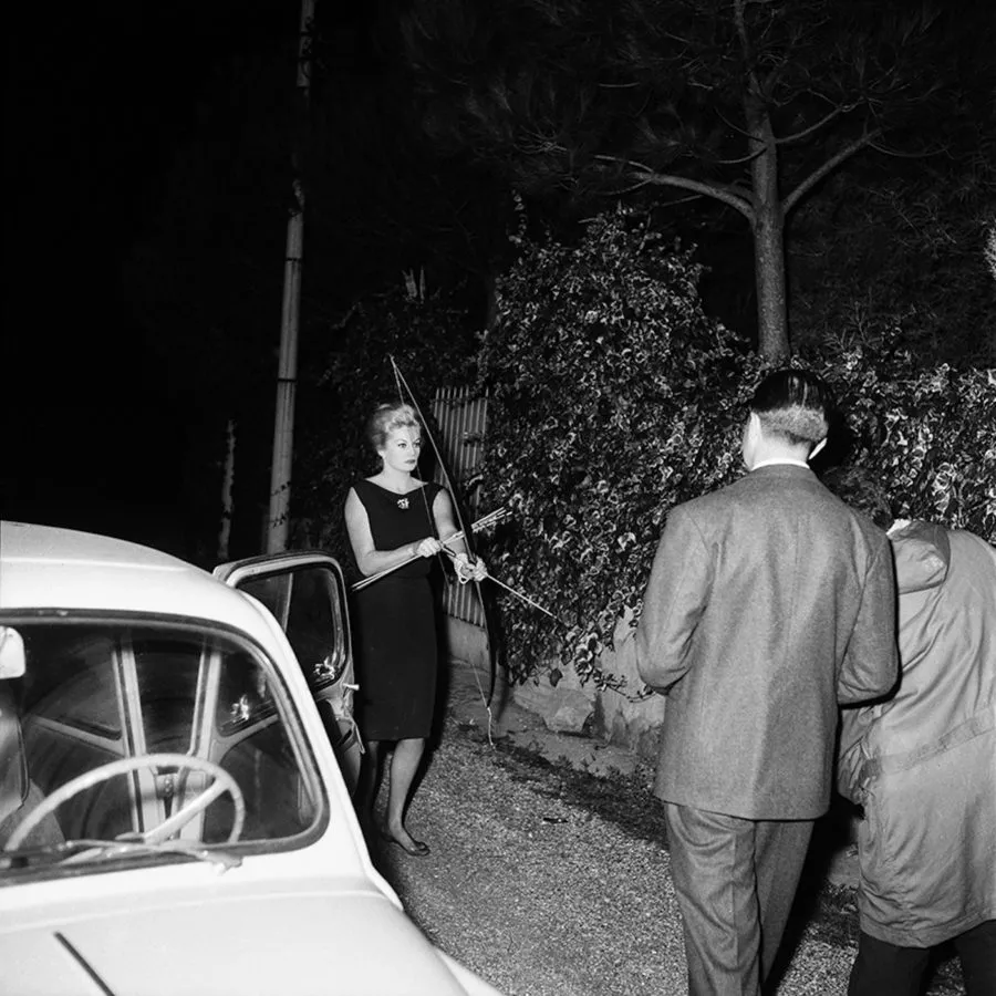 Anita Ekberg empfängt Paparazzi mit Pfeil und Bogen, Rom 1960. Zu sehen n der Ausstellung PAPARAZZI! im WestLicht.
