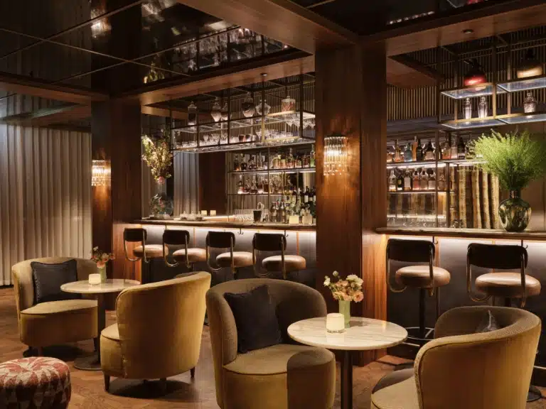 Bar THE1835 mit dunklem Holz, beleuchteten Spirituosenregalen und zentralem Tresen im Rosewood Vienna