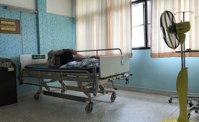 Patient liegt in Krankenhausbett in Thailand mit einfacher Ausstattung nach Roller-Unfall mit Rental Motor Bike.