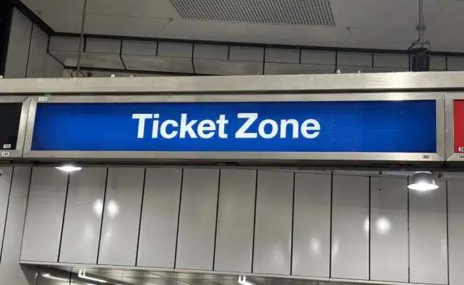Blaues Schild mit Aufschrift Ticket Zone über Zugang zum Bahnsteig