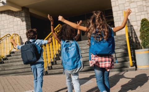 Kinder vor einer Volksschule in Wien beim Schuleintritt mit Schultasche