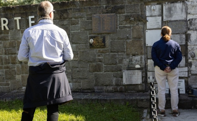 Besucher:innen bei der Erinnerungsmauer der KZ-Gedenkstätte Mauthausen