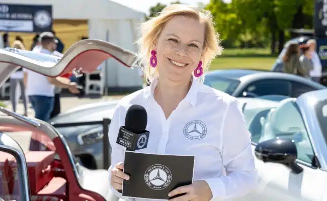 Moderation beim Internationalen SL-Treffen im Schlosspark Laxenburg Moderatorin des Mercedes-Benz SL-Club Austria mit Mikrofon vor historischen Fahrzeugen