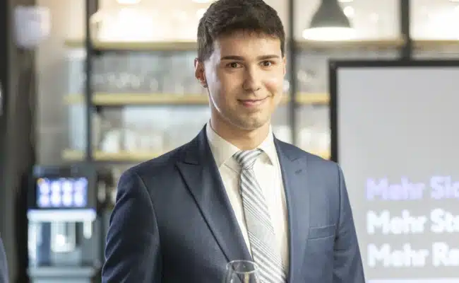 Aleksander Savic im Innenbereich des Wiedner Wein Ecks zwischen Weinregalen und Verkostungsbereich.