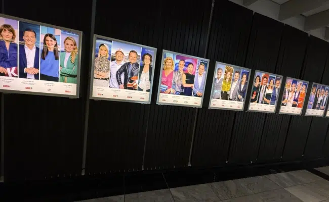 Gerahmte Plakate mit Porträts von ORF-Persönlichkeiten an einer dunklen Wand im ORF-Zentrum.
