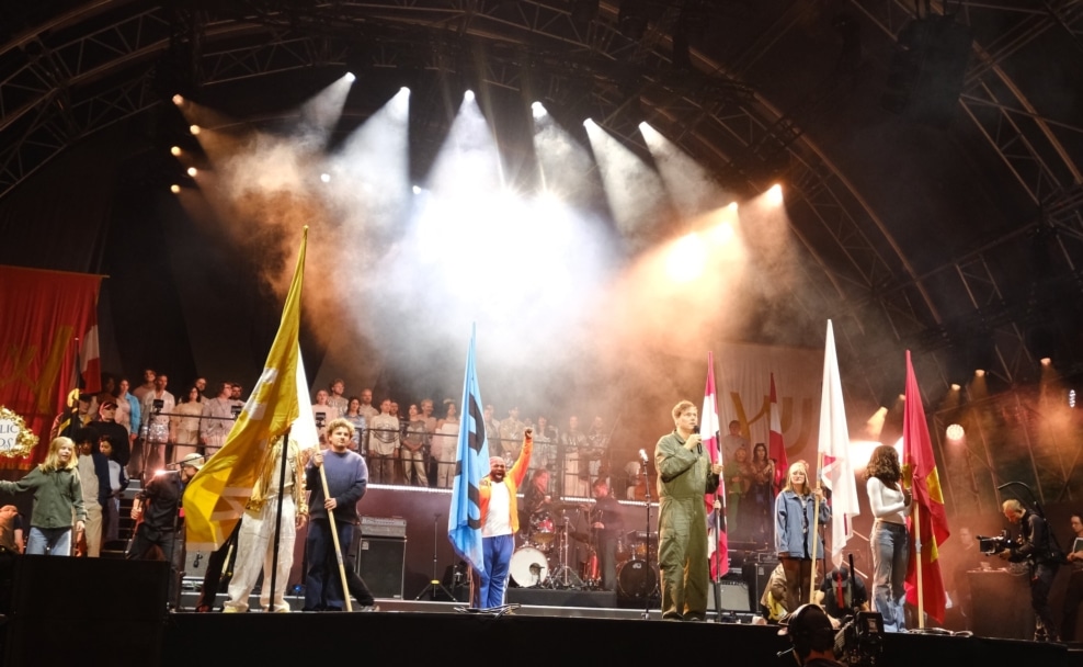 Künstlerinnen, Musiker und der Schmusechor stehen bei der Festwochen-Eröffnung gemeinsam auf der Bühne am Wiener Heldenplatz