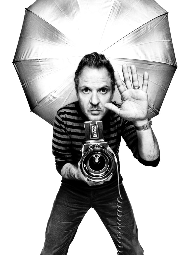 Fotograf Platon mit Hasselblad-Kamera und Studioblitz vor weißem Hintergrund