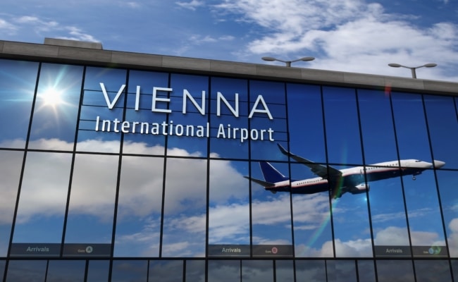 Flughafen Wien mit Flugzeug in einer Spiegelung am Terminalgebäude.