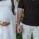 chwangere Frau und Partner halten im Freien Händchen – Symbolbild für Kinderwunsch, Familie und Geburtenrate in Österreich
