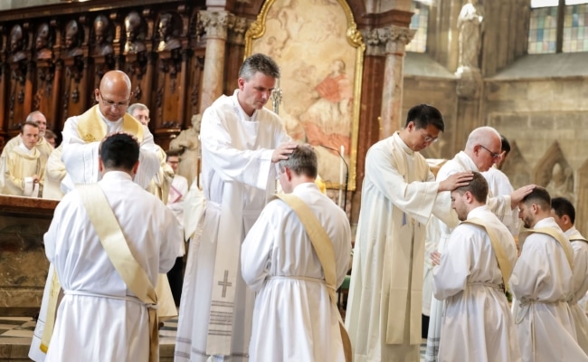 Priester legen den Weihekandidaten während der Priesterweihe im Wiener Stephansdom die Hände auf.