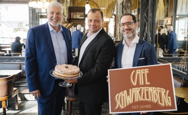 Vertreter der GOURMET Group und des Café Schwarzenberg präsentieren die Jubiläumstorte