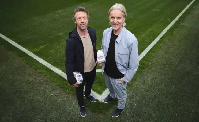 Die Fußball-Experten Jan Åge Fjørtoft und Steffen Freund auf einem Fußballfeld vor der FIFA Fußball-WM 2026.