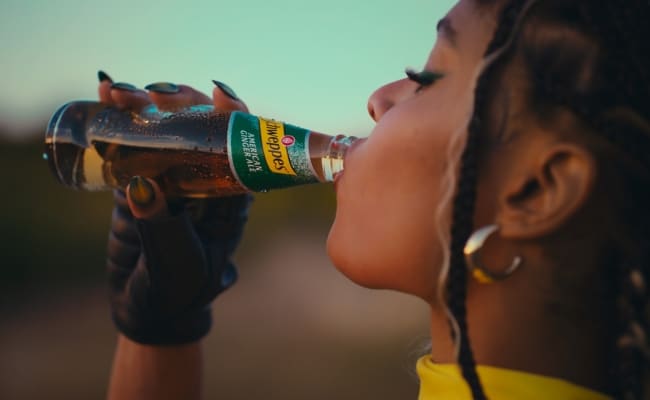 Person trinkt Schweppes American Ginger Ale direkt aus einer Glasflasche