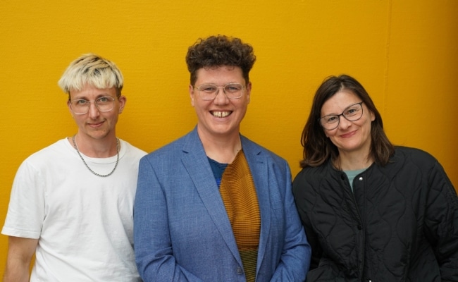 Mitglieder des Projekts Queer Cinema Austria vor gelbem Hintergrund: v.l.: Tirler, Braidt, Kandioler-Biet.