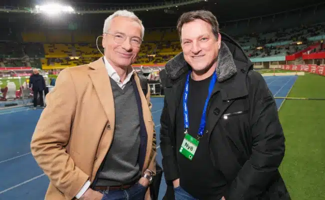 Andreas Herzog und ORF-Moderator Rainer Pariasek am Spielfeldrand eines Fußballstadions.