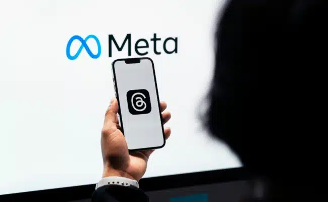 Smartphone mit Threads-App vor einem Bildschirm mit Meta-Logo als Symbolbild für den Meta-Konzern und seine Plattformen.