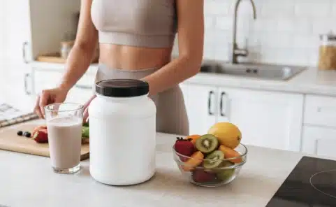 Nahrungsergänzungsmittel und Shake in einer modernen Küche neben frischem Obst.