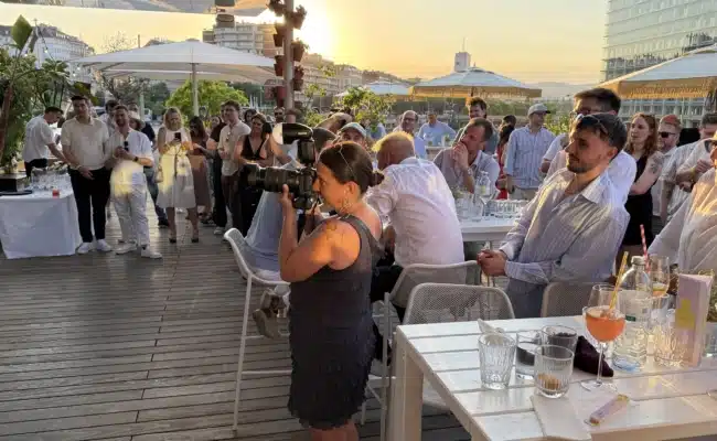 Gäste verfolgen die Ansprache beim 20-Jahr-Jubiläum von WEST4MEDIA im Motto am Fluss in Wien.
