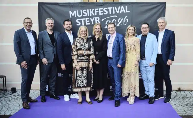 Gruppenfoto von Gästen aus Kultur, Wirtschaft und Politik beim Premierenabend des Musikfestivals Steyr 2026 vor der Fotowand.