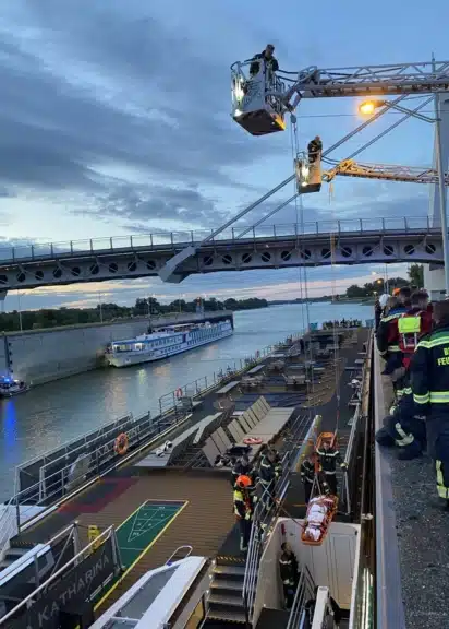 Einsatzkräfte der Berufsfeuerwehr Wien bergen eine verletzte Person mit einer Drehleiter vom Flusskreuzfahrtschiff in der Schleuse Freudenau.