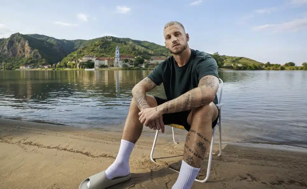 Marko Arnautović sitzt für die neue Kampagne der Niederösterreich Werbung auf einem Klappstuhl am Donauufer in der Wachau.
