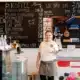 Mitarbeiterin im Mamas Café am Stephansplatz in Wien vor der Kaffeekarte und Kuchentheke
