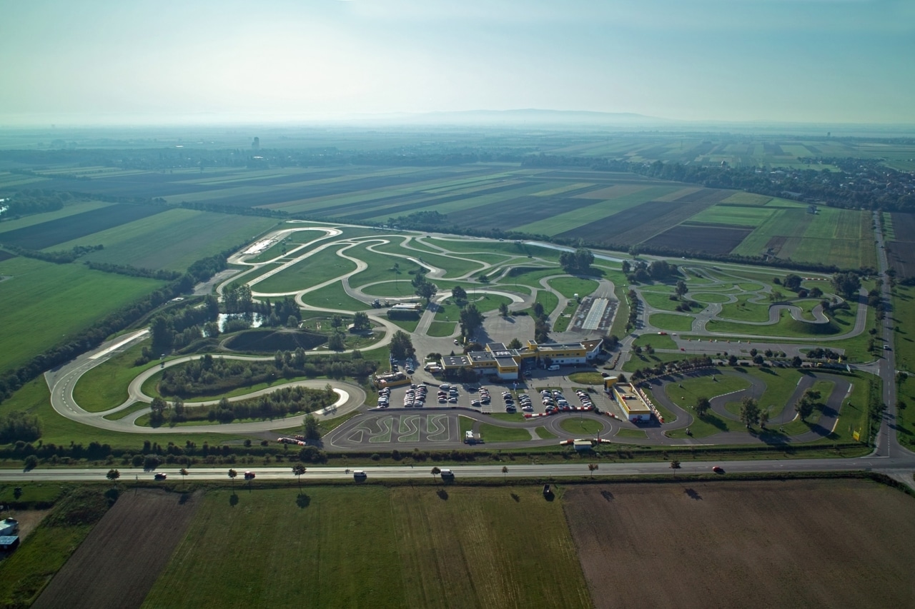 Luftaufnahme des ÖAMTC Fahrtechnikzentrums Teesdorf mit mehreren Fahrparcours, Gebäuden und Parkflächen inmitten von Feldern.