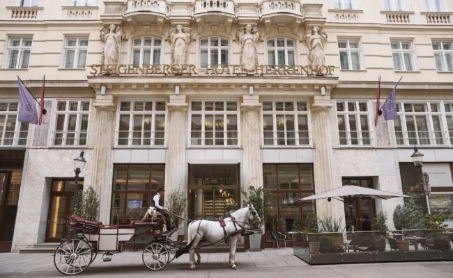 Außenansicht des Steigenberger Hotel Herrenhof Wien mit Fiaker in der Herrengasse.