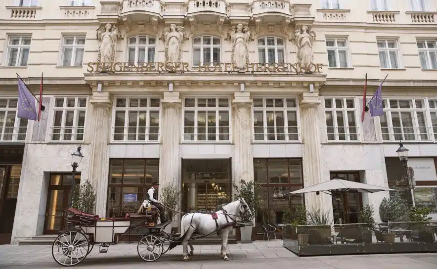 Außenansicht des Steigenberger Hotel Herrenhof Wien mit Fiaker in der Herrengasse.