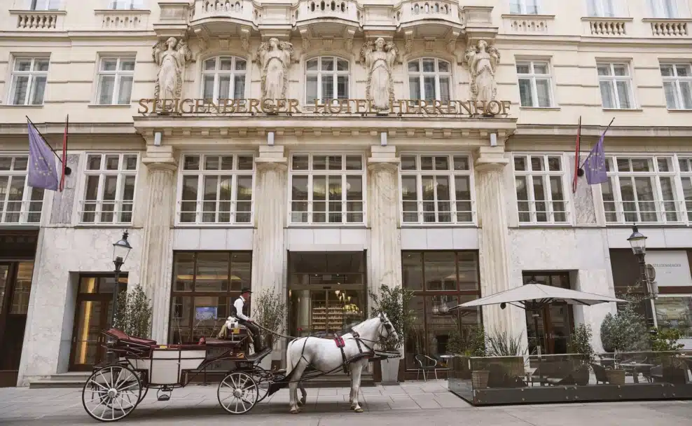Außenansicht des Steigenberger Hotel Herrenhof Wien mit Fiaker in der Herrengasse.