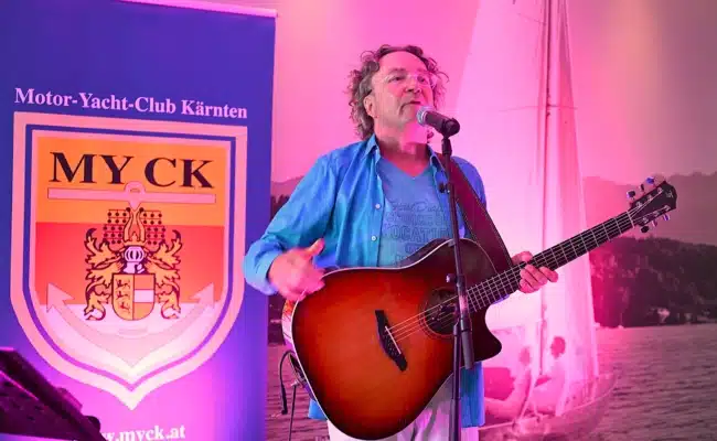 Thomas Strobl auf der Bühne beim MYCK-Sommerfest Thomas Strobl mit Gitarre auf der Bühne beim Sommerfest des MYCK in VeldenThomas Strobl mit Gitarre auf der Bühne beim Sommerfest des MYCK in Velden