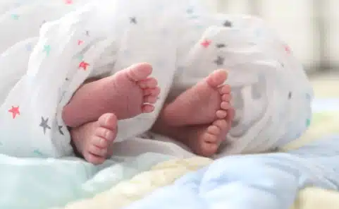 Füße von Neugeborenen unter einer Babydecke als Symbolbild für die beliebtesten Babynamen Emma und Noah in Österreich 2025.