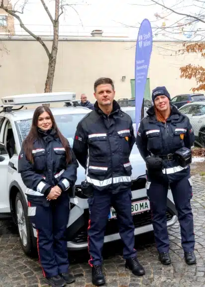 Drei Beschäftigte der Wiener Parkraumüberwachung stehen vor einem Kamera-Auto.