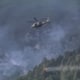 Ein AW169 Lion des Bundesheeres transportiert einen Löschwasserbehälter über bewaldetem Berggelände.