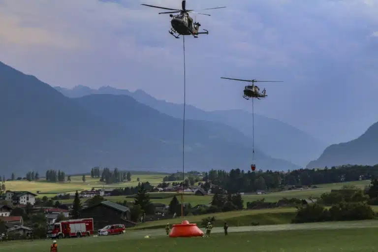 Zwei Hubschrauber des Bundesheeres transportieren Löschwasser über einem alpinen Einsatzgebiet.