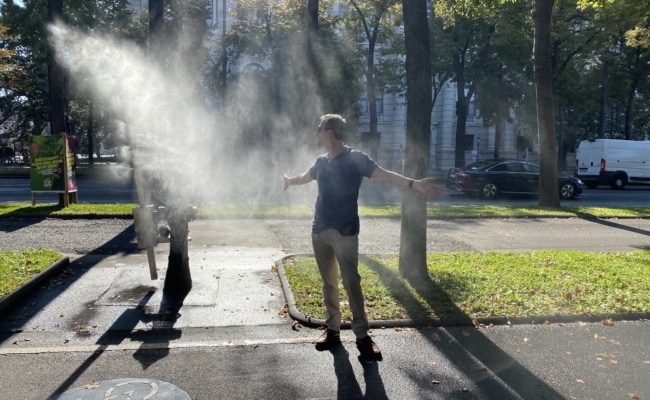 Ein Mann nutzt eine Sprühnebelanlage am Wiener Opernring zur Abkühlung. Die sogenannten Sommerspritzer werden auf Hydranten montiert und sollen an heißen Tagen punktuell für Erfrischung sorgen.