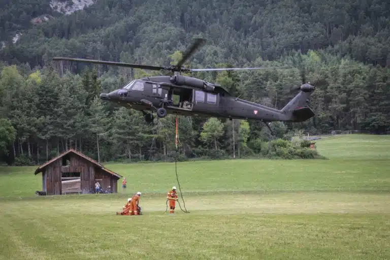 Feuerwehrkräfte befestigen die Außenlast eines S-70 Black Hawk des Bundesheeres.