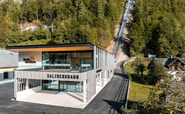 Neue Talstation der Salzbergbahn Hallstatt mit der steilen Trasse durch den bewaldeten Berghang