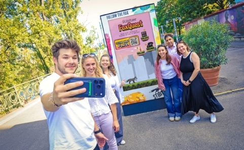Sechs Projektbeteiligte spielen vor einem digitalen Stibitzer-FoxQuest-Screen per Smartphone.