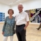 Agnes und Karlheinz Essl lächelnd vor Roy Lichtensteins „Modern Tapestry“ in der ALBERTINA Klosterneuburg