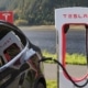 Schwarzer Tesla beim Laden an einem Supercharger vor einer Berglandschaft