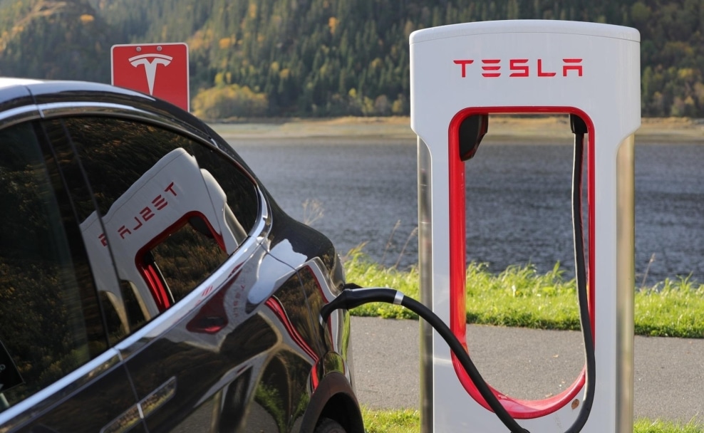Schwarzer Tesla beim Laden an einem Supercharger vor einer Berglandschaft