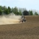 Traktor auf einem trockenen Acker mit großer Staubwolke