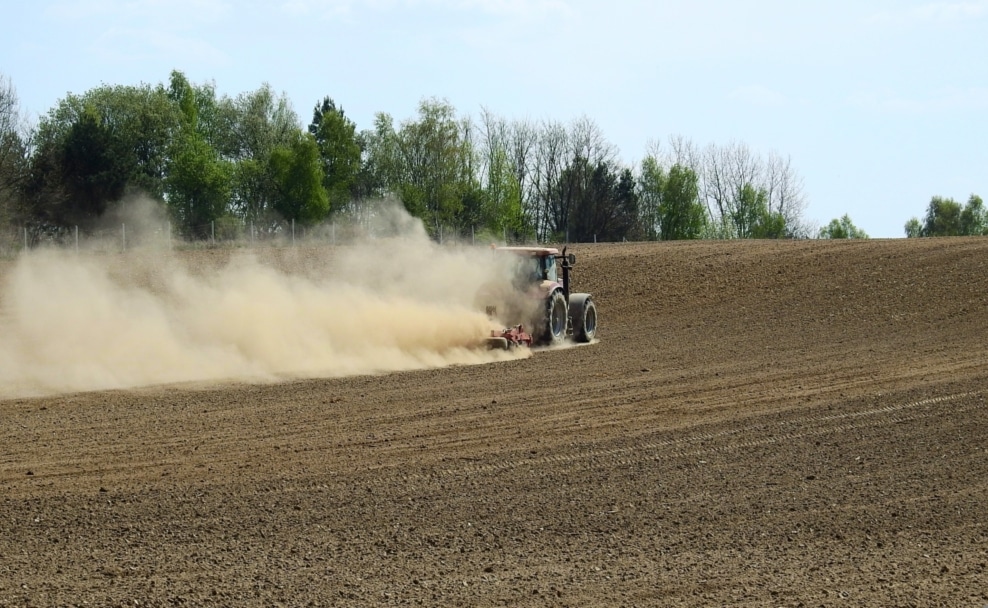 Traktor auf einem trockenen Acker mit großer Staubwolke