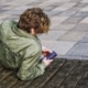 Jugendlicher sitzt mit Kopfhörern auf einer Bank und benutzt ein Smartphone.