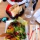 Gedeckter Restauranttisch mit Wasserkaraffe, Glas Wasser, Salat und Brotkorb