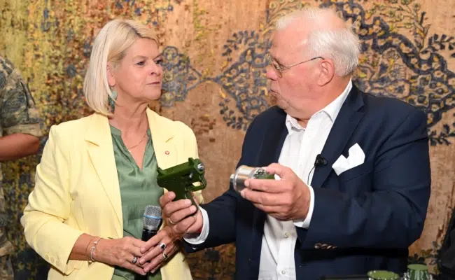 Christian Wehrschütz hält eine Anti-Drohnenpistole und einen separaten runden Einsatz in den Händen und zeigt beides Klaudia Tanner.