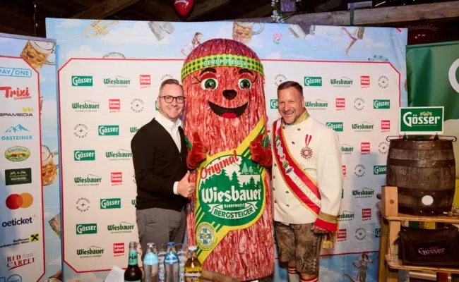 Roland Schmid und Wiesn Kaiser Johann Pittermann posieren mit der Wiesbauer Werbefigur Bergsteiger