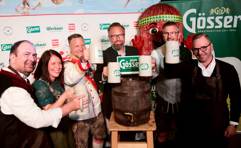 ertreter der Wiener Kaiser Wiesn und ihrer Partner stoßen vor einer Gösser Werbewand mit Bierkrügen an